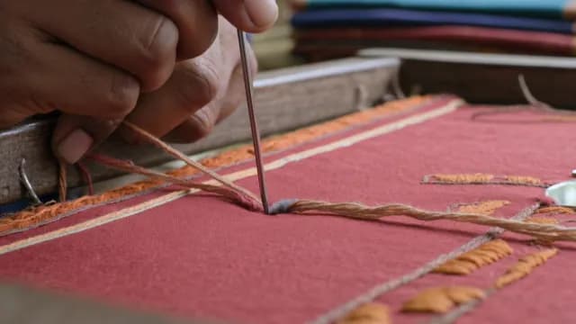 Close-up of Artisan Hands Performing Traditional Embroidery on Red Fabric
