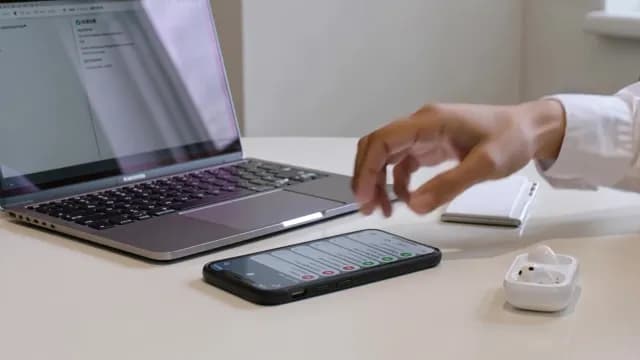 Modern Workspace with Laptop Smartphone and Wireless Earbuds on White Desk