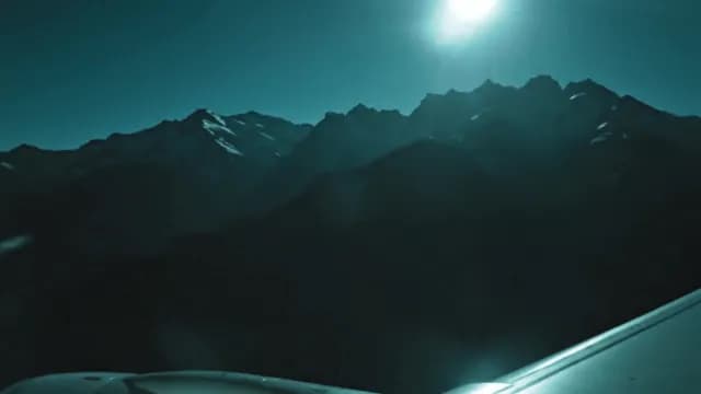 Cinematic Aerial View of Rugged Mountain Peaks Under Bright Moonlight
