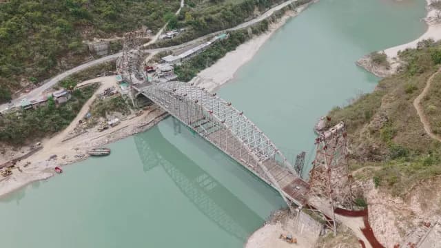 Aerial View of Steel Arch Bridge Construction Over Turquoise Alaknanda River, Rudraprayag Road, Uttarakhand in Mountains