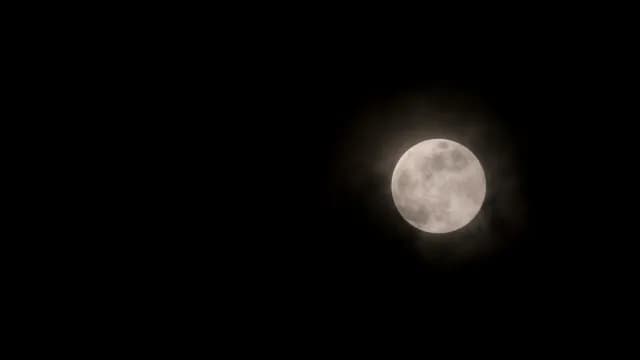 Full Moon Glowing Through Hazy Clouds in Dark Night Sky