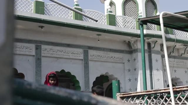 Young Girl in Red Hijab Outside a Traditional Mosque with Calligraphy View of Bu Ali Shah Qalandar Dargah Panipat, Haryana, India