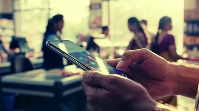 Person Using Smartphone While Waiting in Supermarket Checkout Line