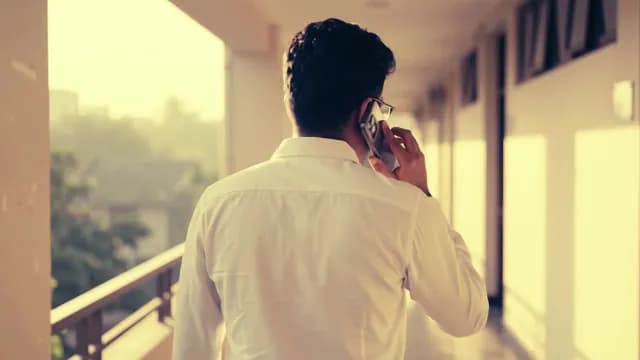 Businessman Talking on Smartphone While Walking Through a Bright Office Hallway