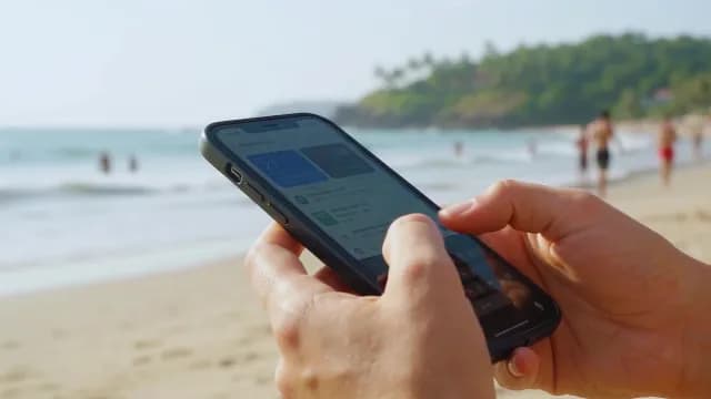 Person Using Smartphone on a Tropical Beach During Vacation